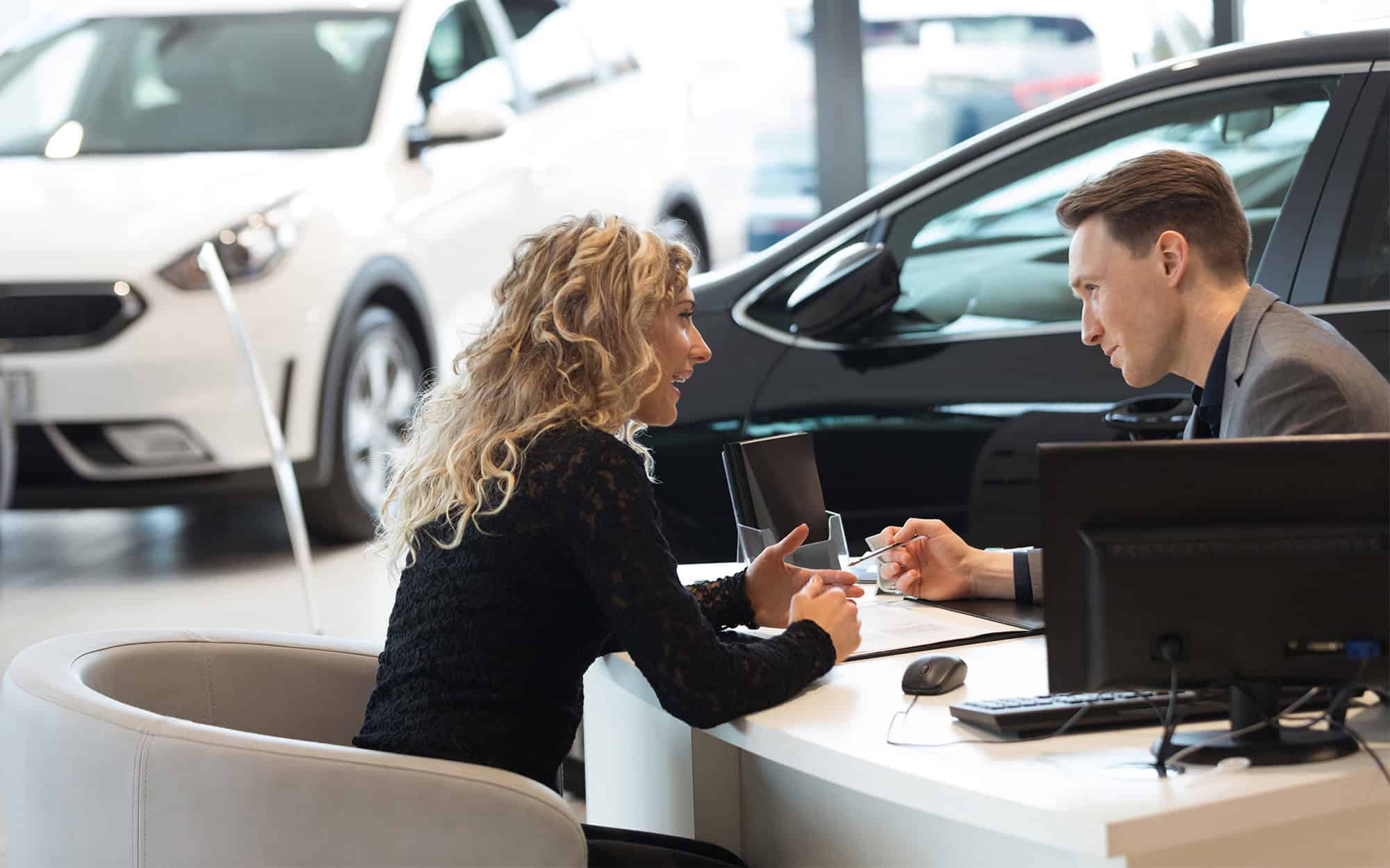 Happy female customer talking with salesman in showroom