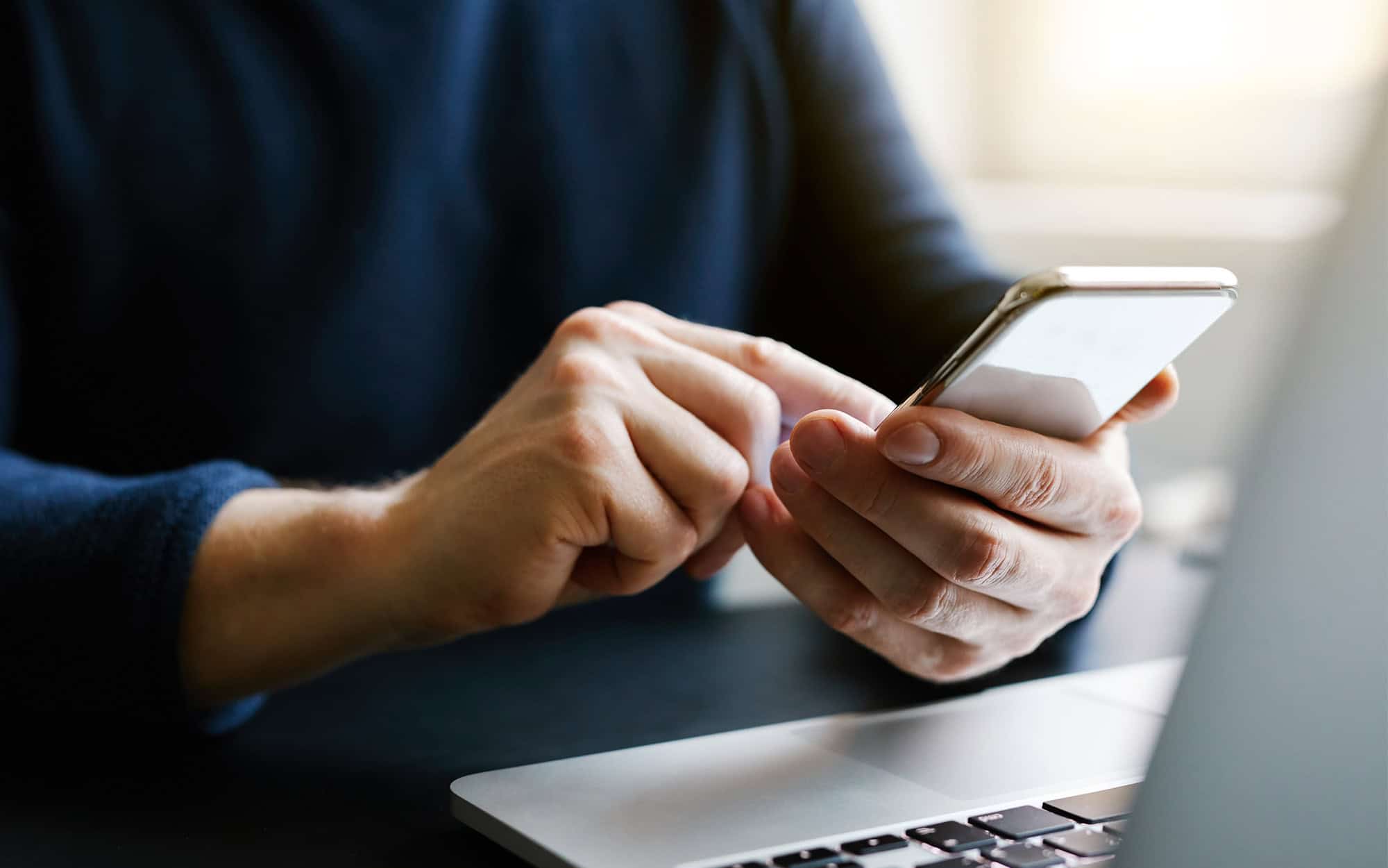 Man with a finger on the screen using a mobile phone in the office