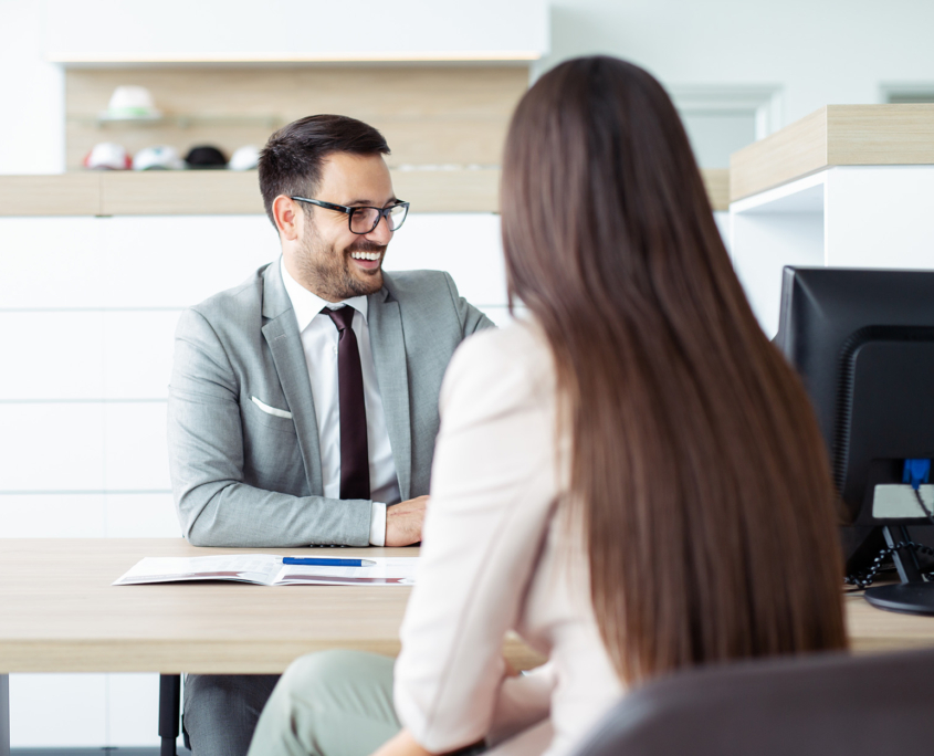 Car salesperson discussing with female customer while sitting in showroom